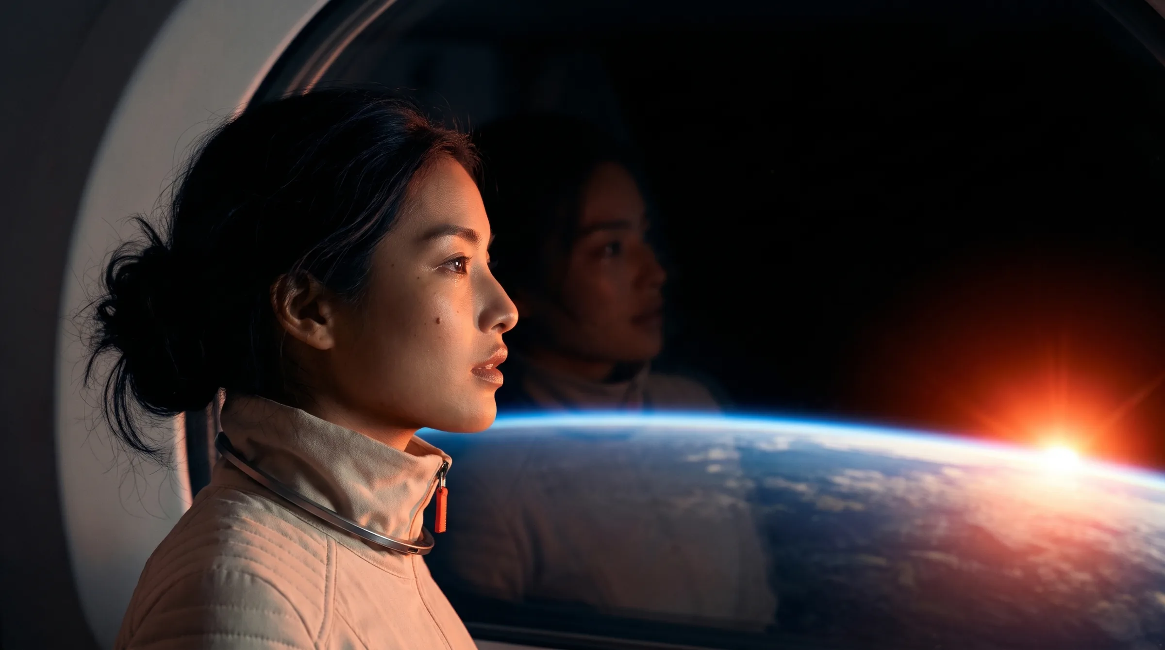 Her profile at the window as the sun rises over the curve of the Earth